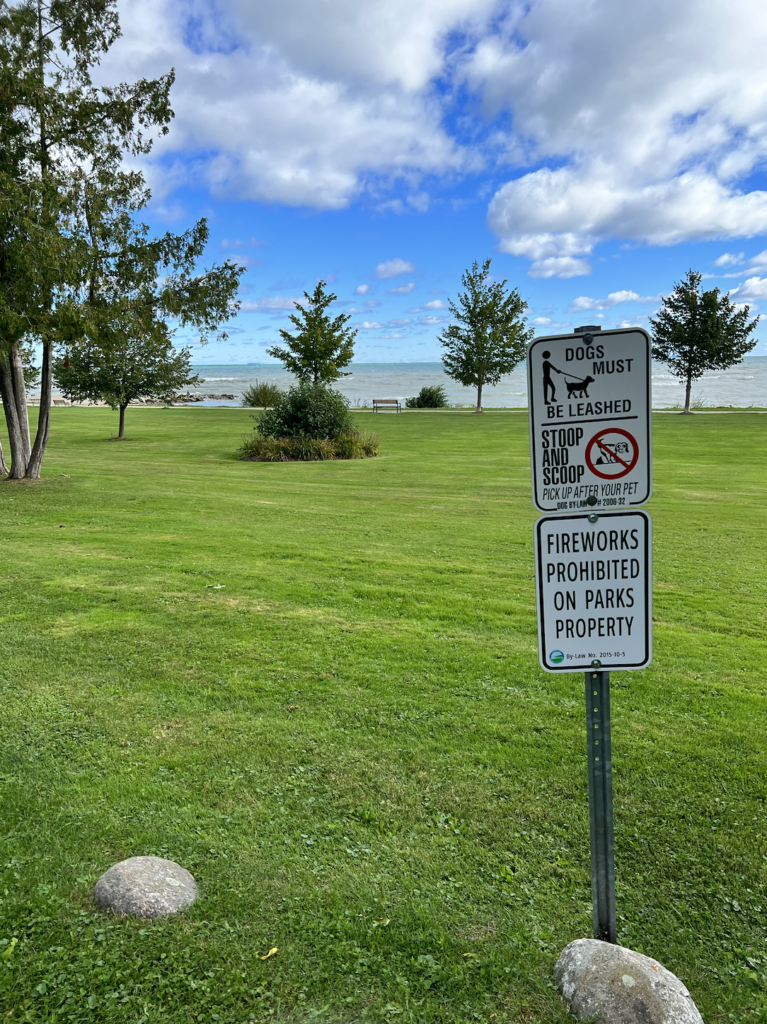 Bayview Park water views and sign that says Dogs must be leashed, stoop and scoop (we encourage you to scoop 2) 